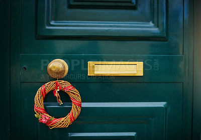 Buy stock photo Closeup of a green door with a Christmas decoration hanging on the handle outside during the day