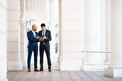 Buy stock photo Shot of young handsome businessmen using a cellphone together outside