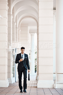 Buy stock photo Shot of a young handsome businessman using a cellphone outside