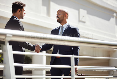 Buy stock photo Cropped shot of young handsome businessmen shaking hands on a bridge outside