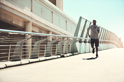 Buy stock photo Shot of a handsome young man running on a bridge in the city