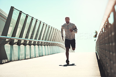 Buy stock photo Shot of a handsome young man running on a bridge in the city
