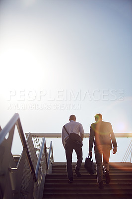 Buy stock photo Low angle shot of unrecognizable businessmen walking up stairs outside