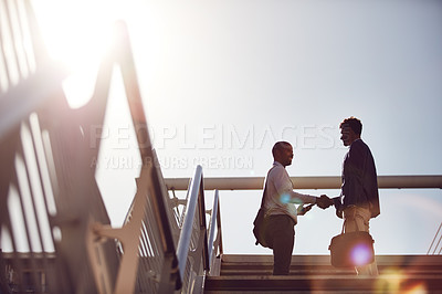 Buy stock photo Low angle shot of young handsome businessmen shaking hands on top of a staircase outside