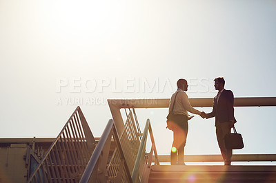 Buy stock photo Low angle shot of young handsome businessmen shaking hands on top of a staircase outside