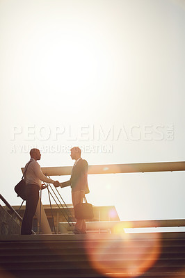 Buy stock photo Low angle shot of two businessmen shaking hands on top of a staircase outside