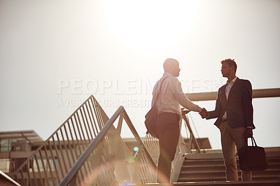 Buy stock photo Cropped shot of handsome businessmen shaking hands on top of a staircase outside