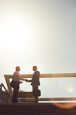 Buy stock photo Shot of handsome businessmen shaking hands on top of a staircase outside