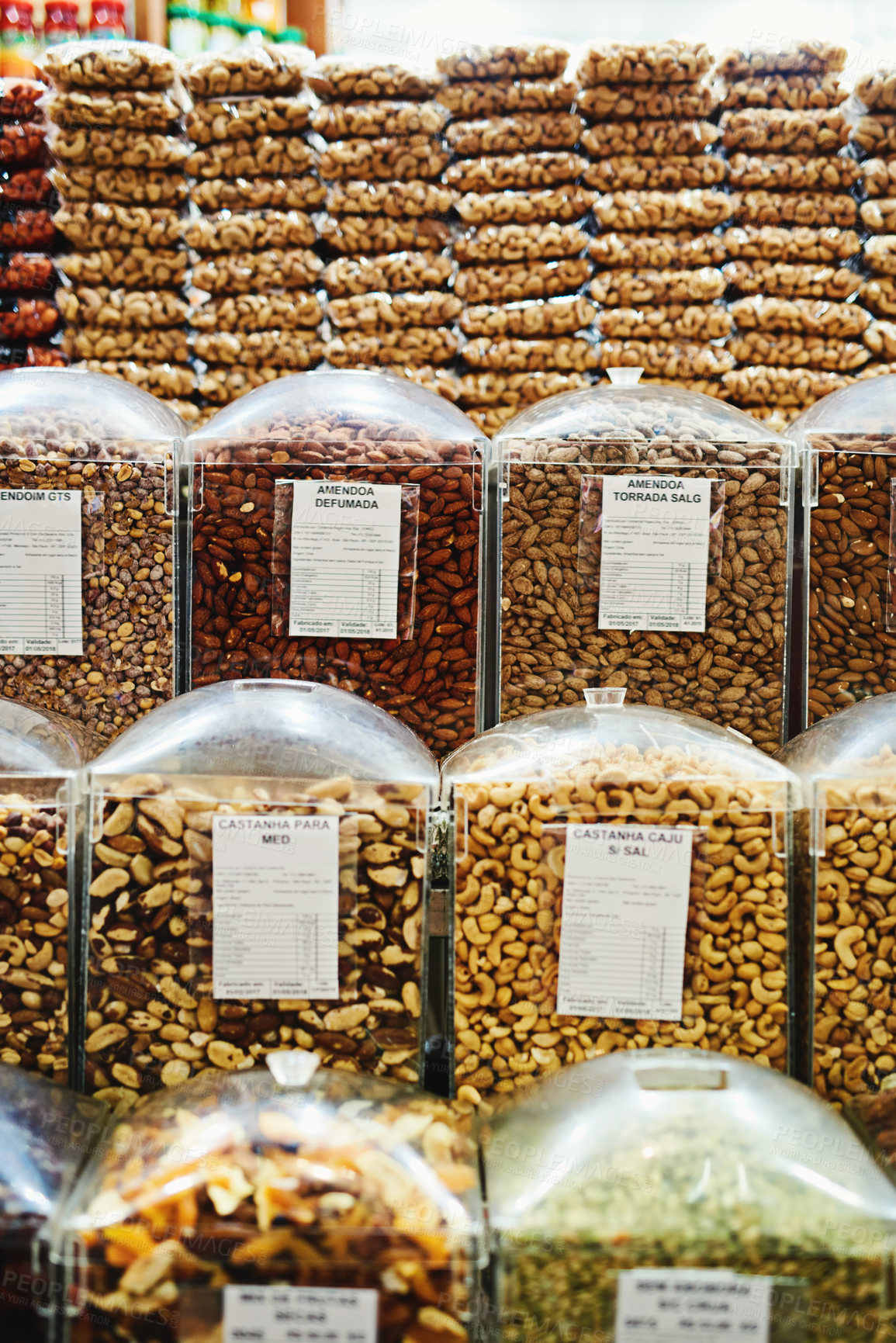 Buy stock photo Shot of a whole bunch of containers and packets full of nuts that are being displayed at a market