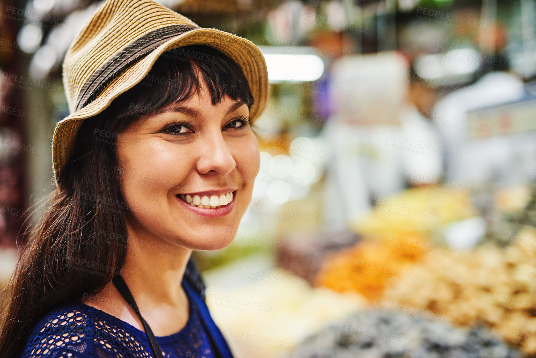 Buy stock photo Portrait of a cheerful young woman standing in the middle of a busy market outside during the day