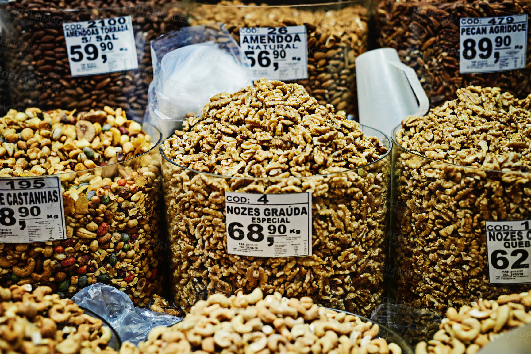 Buy stock photo Shot of containers filled with different types of nuts and put on display to be sold at a market during the day