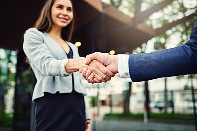 Buy stock photo Cropped shot of a beautiful young businesswoman shaking hands with an unrecognizable businessman outside