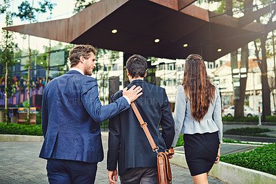 Buy stock photo Rearview shot of unrecognizable businesspeople walking to a building together outside