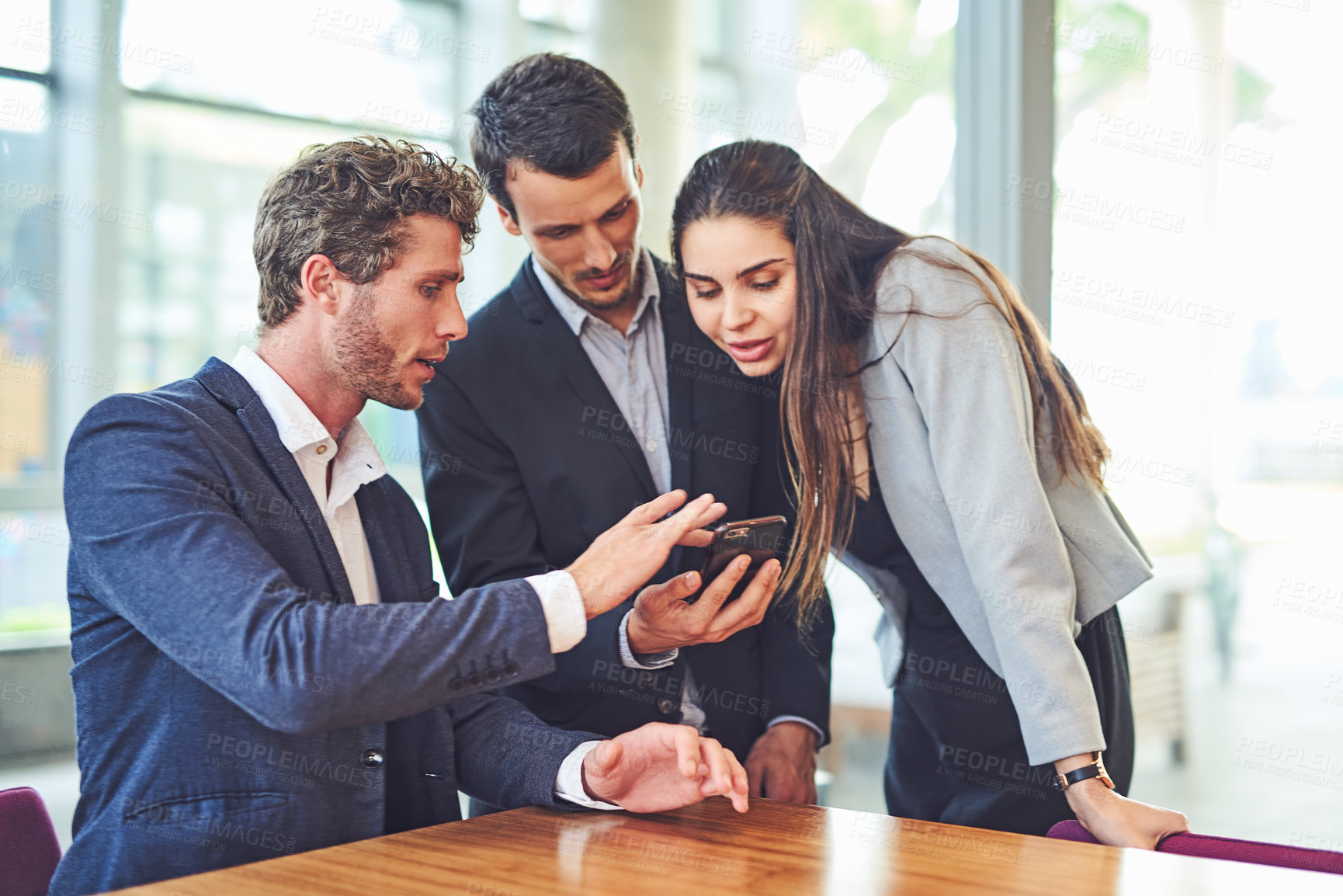 Buy stock photo Cropped shot of businesspeople using a cellphone together indoors