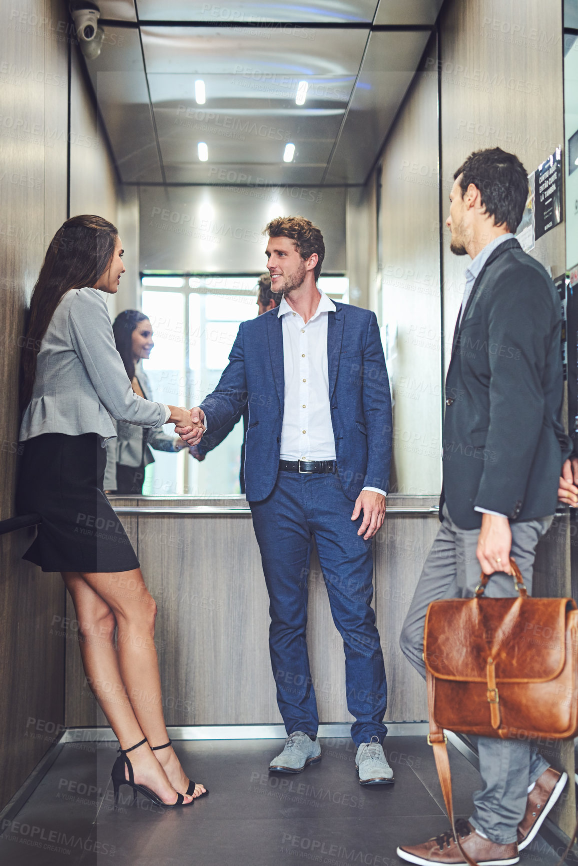 Buy stock photo Shot of businesspeople meeting and greeting in an elevator