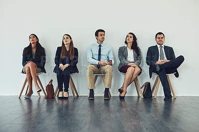 Buy stock photo Studio shot of a group of businesspeople looking bored while waiting in line