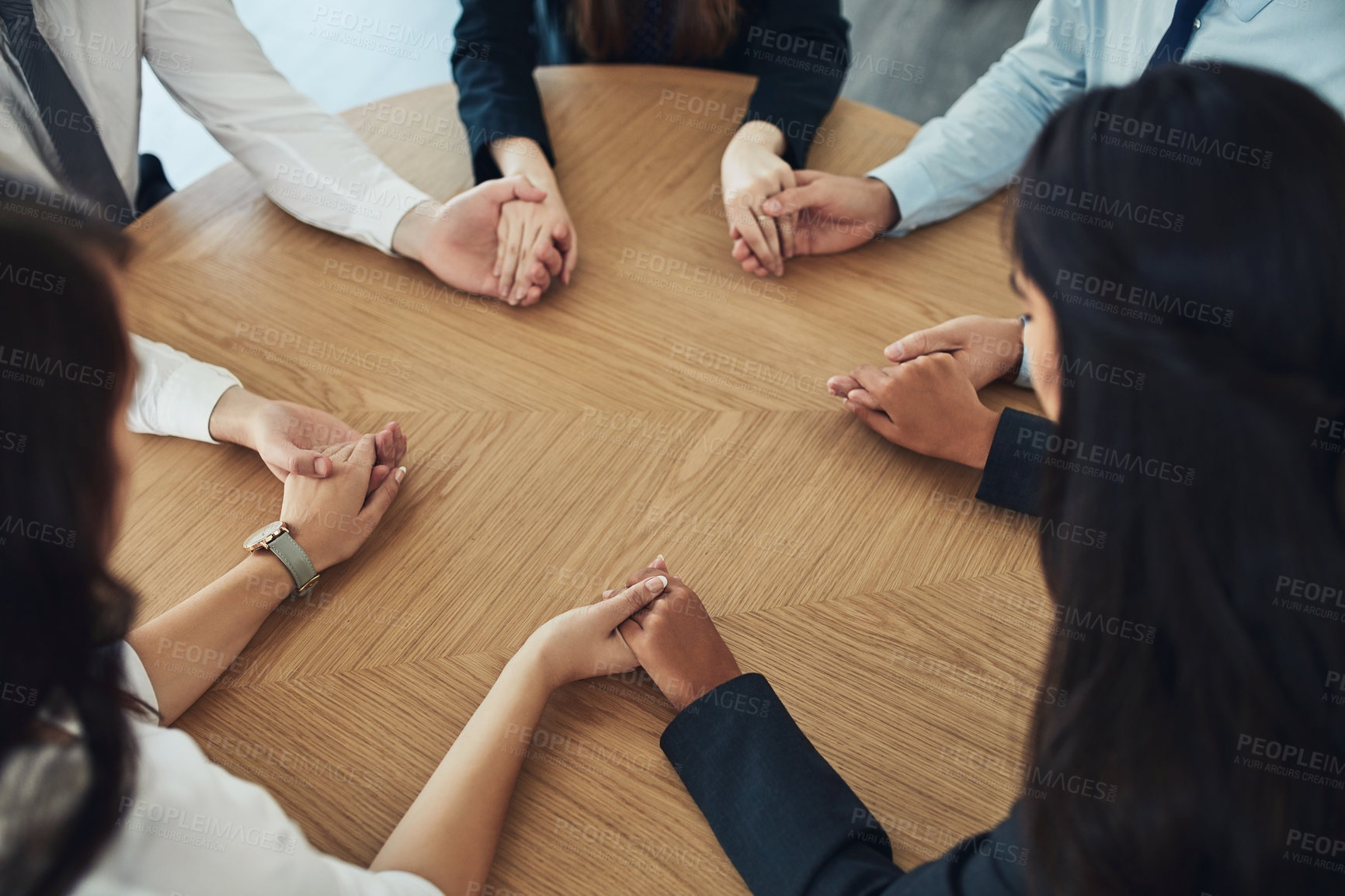 Buy stock photo Cropped shot of a group of businesspeople sitting together at a table and holding hands
