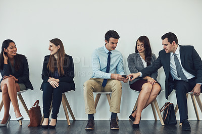Buy stock photo Studio shot of a group of businesspeople using wireless technology while waiting in line