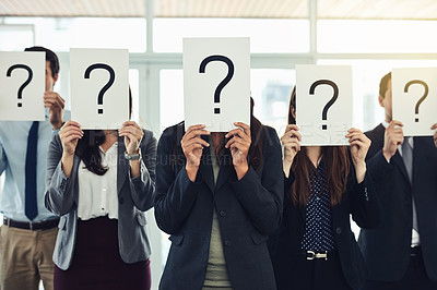Buy stock photo Shot of a group of businesspeople holding questions marks in front of their faces