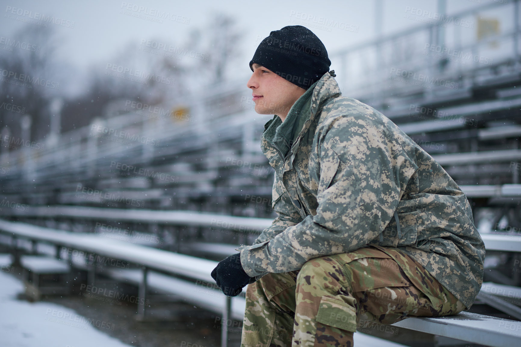 Buy stock photo Shot of a young soldier sitting outside on a snowy day at military school and looking thoughtful