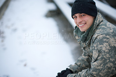 Buy stock photo Shot of a young soldier sitting outside on a snowy day