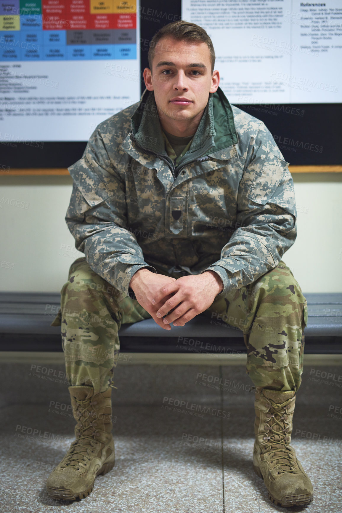 Buy stock photo Shot of a young soldier sitting on a bench in the hall of a military academy