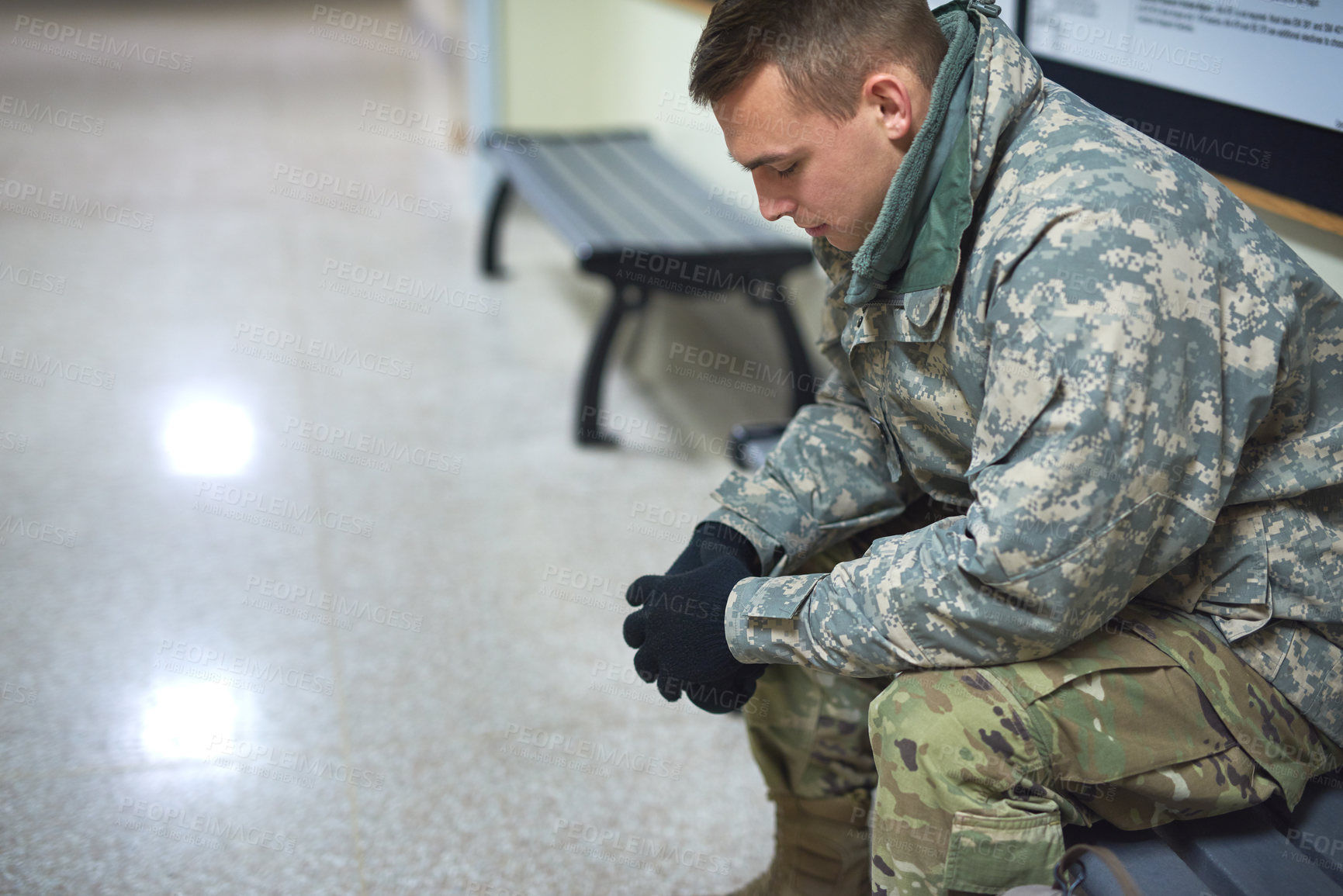 Buy stock photo Shot of a young soldier sitting on a bench in the hall of a military academy