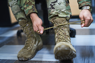 Buy stock photo Cropped shot of a soldier tying his boot shoelaces in the dorms of a military academy