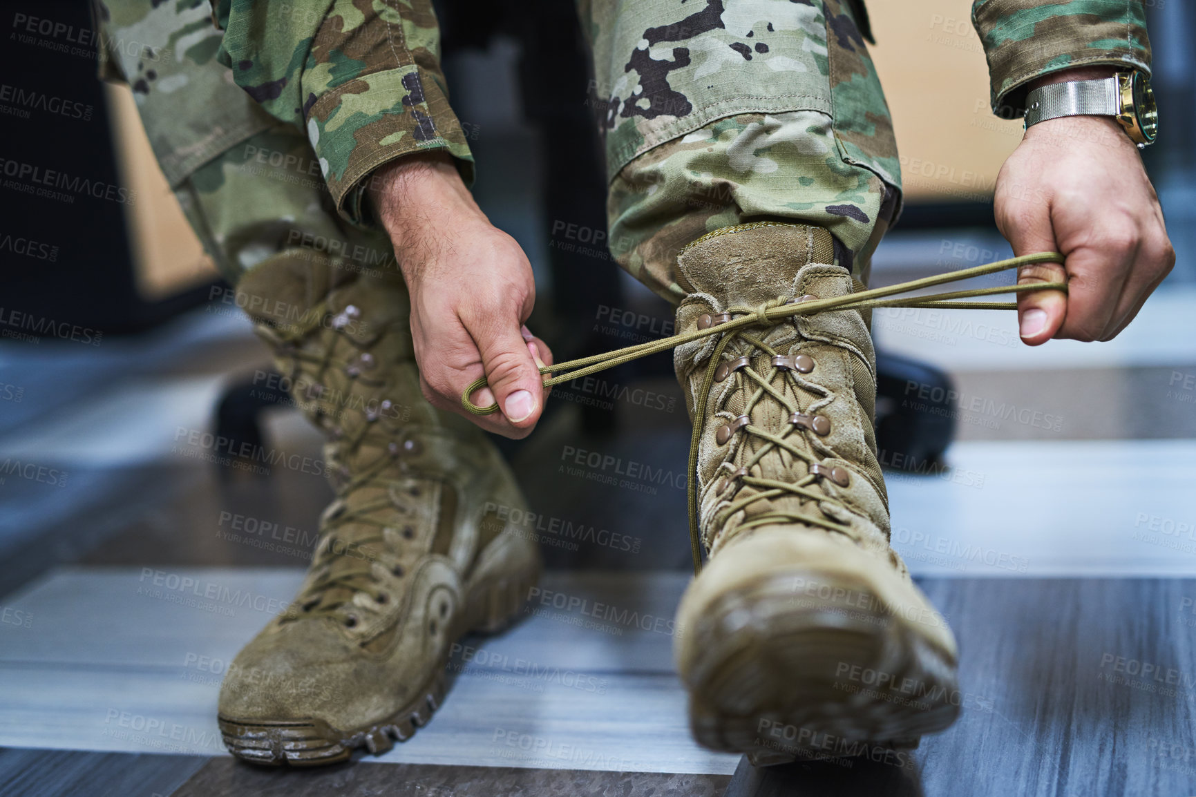 Buy stock photo Cropped shot of a soldier tying his boot shoelaces in the dorms of a military academy
