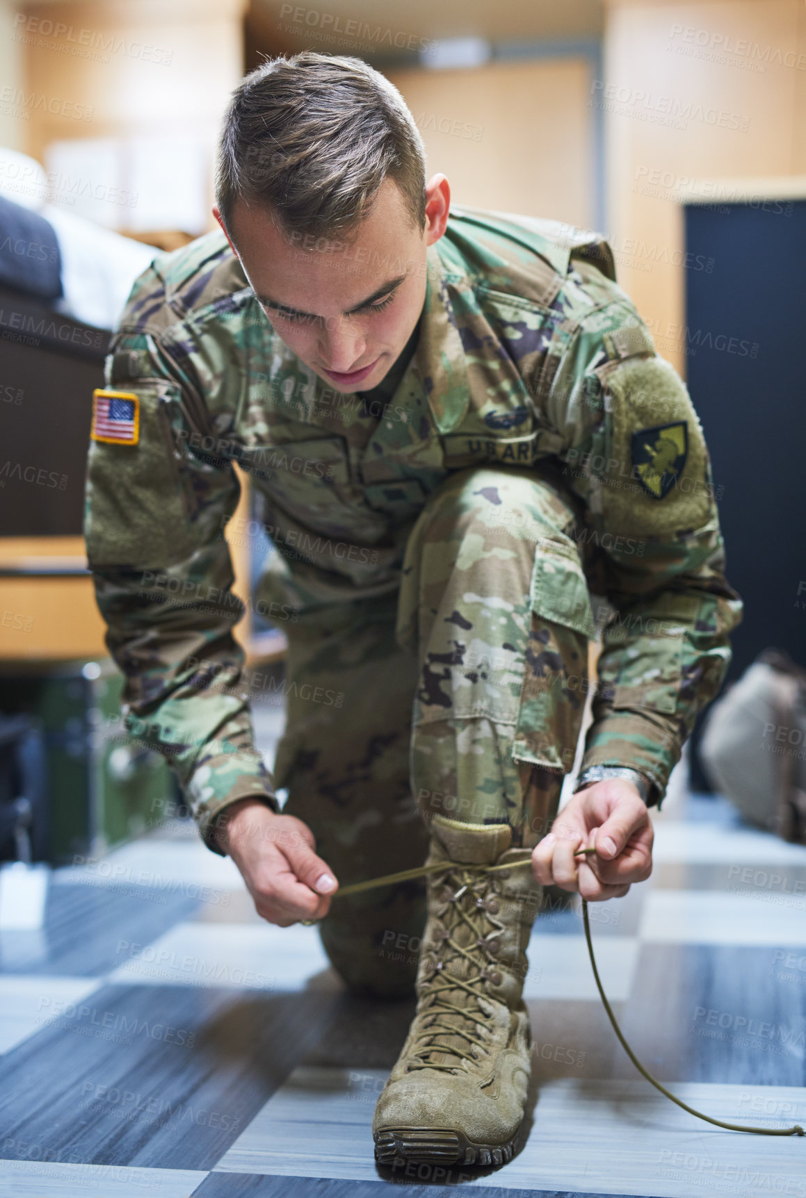 Buy stock photo Shot of a young soldier tying his boot shoelaces in the dorms of a military academy