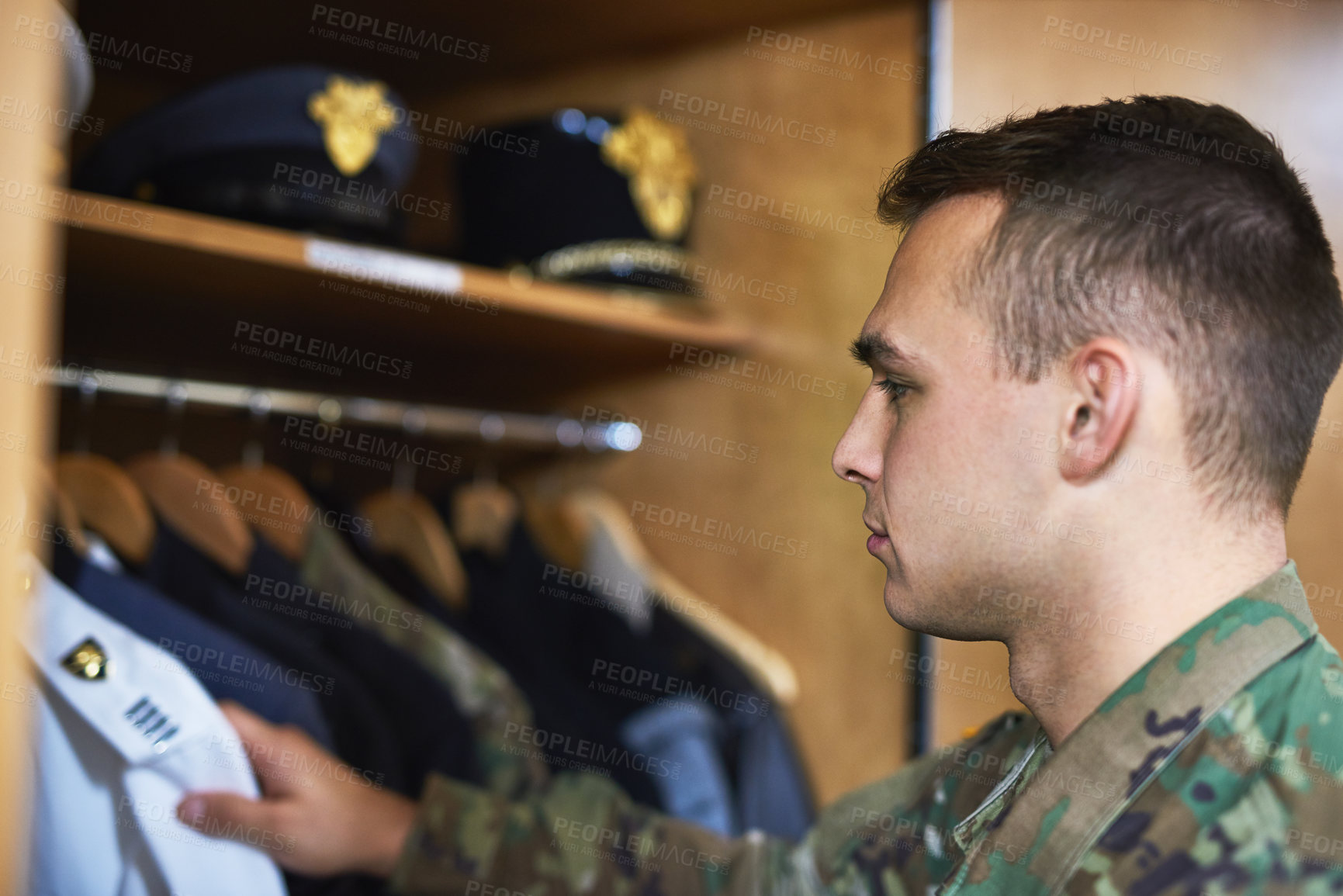 Buy stock photo Shot of a young soldier standing getting dressed in the dorms of a military academy