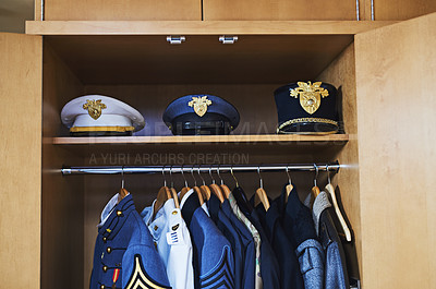 Buy stock photo Shot of various military jackets and hats hanging in a closet