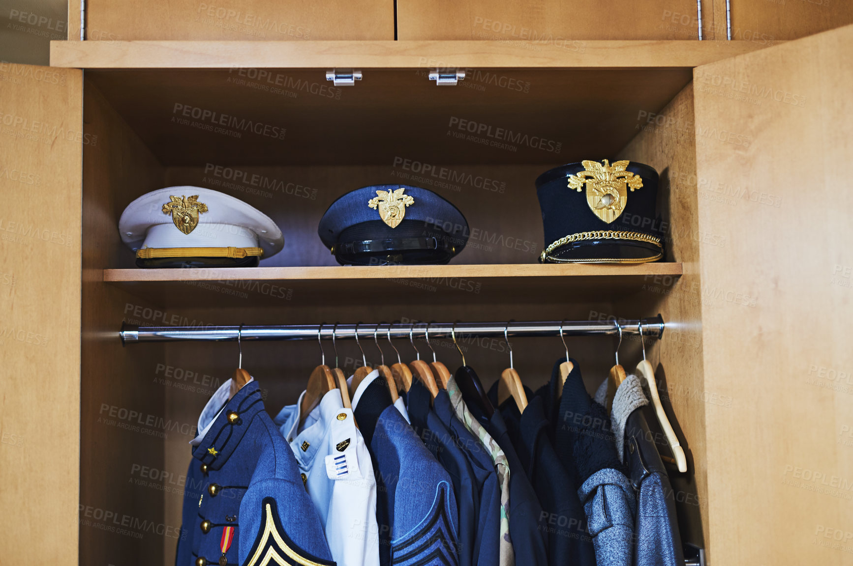 Buy stock photo Shot of various military jackets and hats hanging in a closet