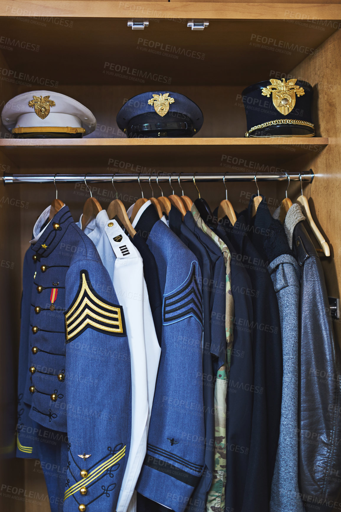 Buy stock photo Shot of various military jackets and hats hanging in a closet