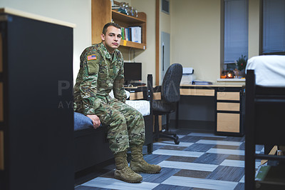 Buy stock photo Shot of a young soldier sitting on his bed in the dorms of a military academy