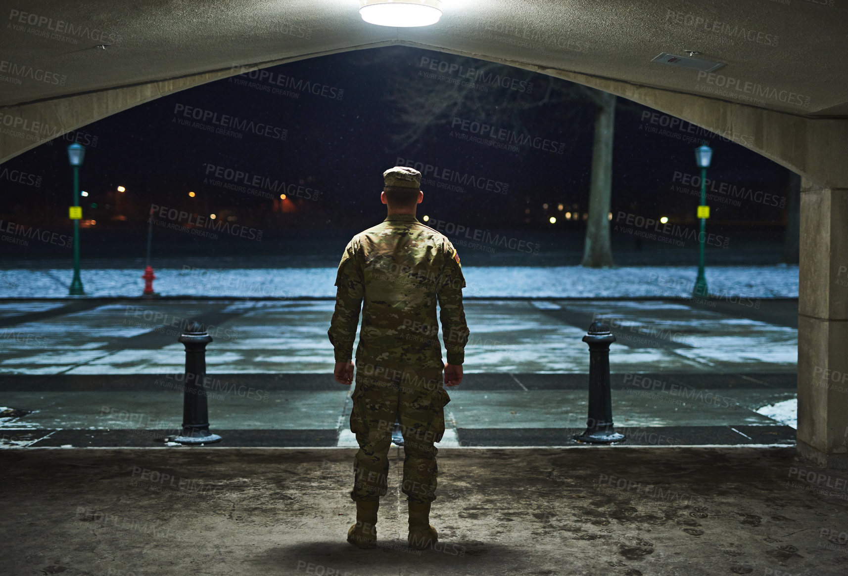 Buy stock photo Rearview shot of a young soldier standing outside on a cold night at a military academy