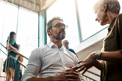 Buy stock photo Shot of two businesspeople talking to each other while standing on a stairwell