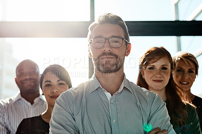 Buy stock photo Cropped shot of a businessman posing with his arms crossed with his colleagues in the background