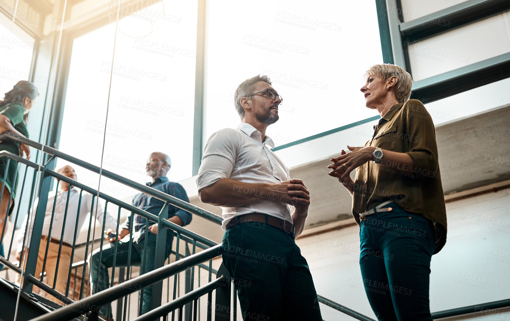 Buy stock photo Shot of two businesspeople talking to each other while standing on a stairwell