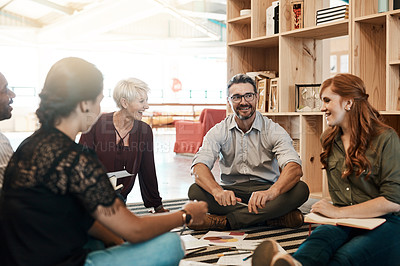 Buy stock photo Shot of a group of businesspeople having a brainstorming session while sitting on the floor