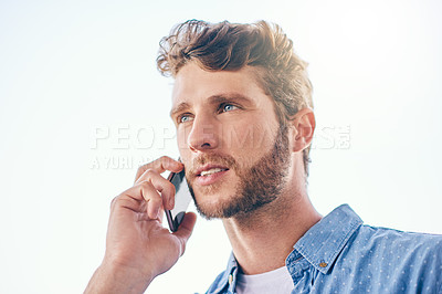 Buy stock photo Shot of a confident young man talking on his cellphone outside during the day