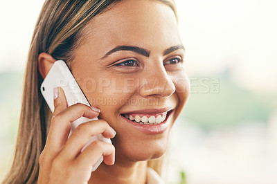 Buy stock photo Shot of a cheerful young woman talking on her cellphone while standing inside of a cafe during the day