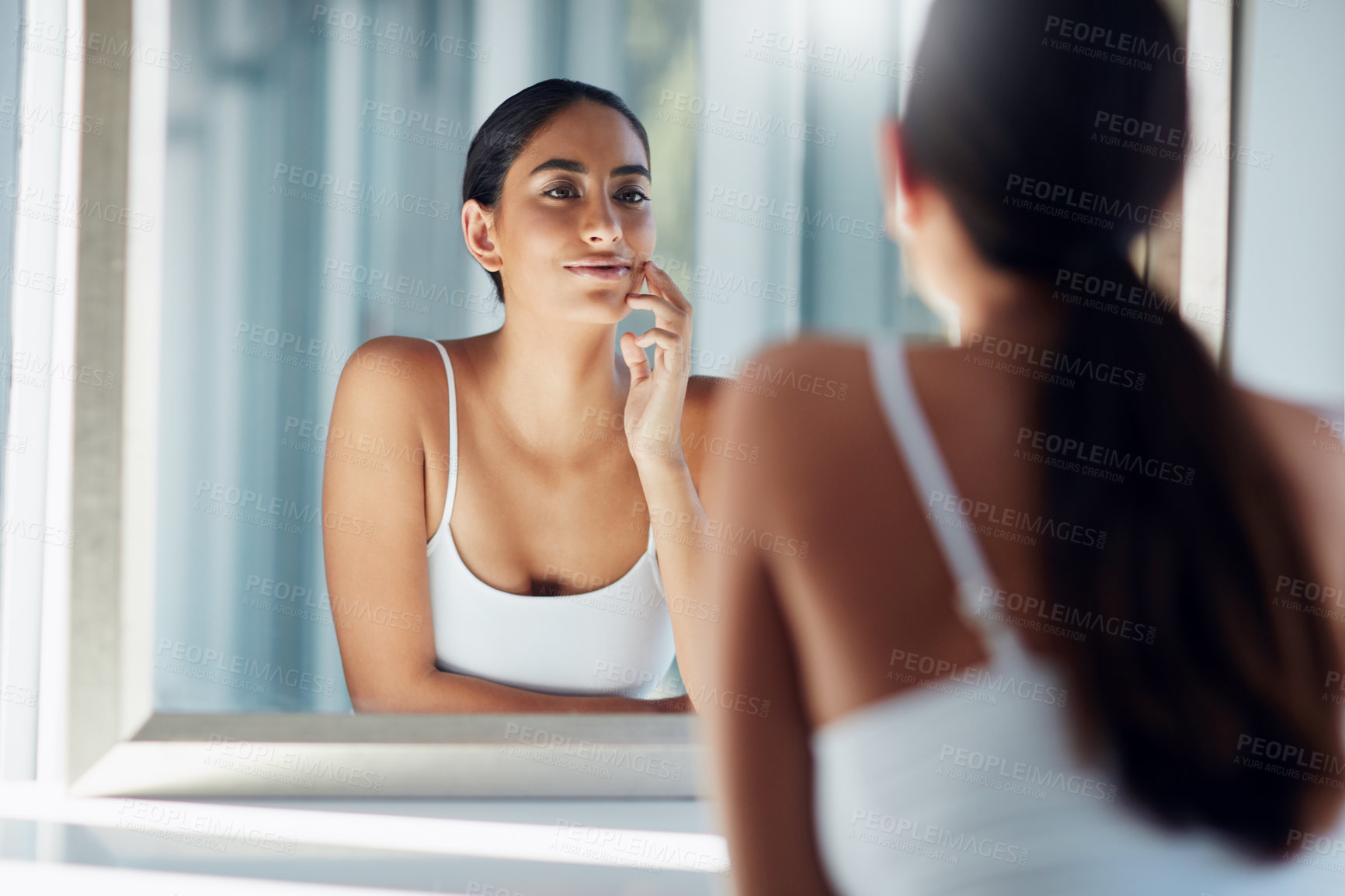 Buy stock photo Cropped shot of an attractive young woman inspecting her skin in front of the bathroom mirror