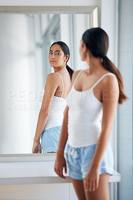 Buy stock photo Cropped shot of an attractive young woman inspecting her back in front of the bathroom mirror