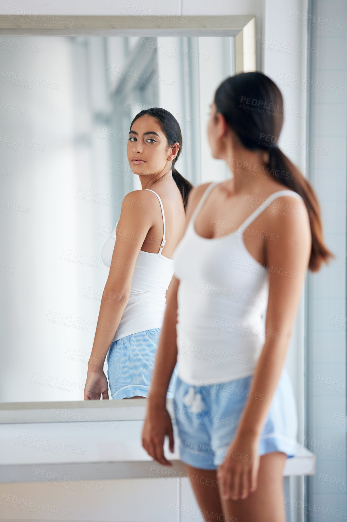 Buy stock photo Cropped shot of an attractive young woman inspecting her back in front of the bathroom mirror