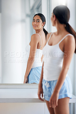 Buy stock photo Cropped shot of an attractive young woman inspecting her back in front of the bathroom mirror