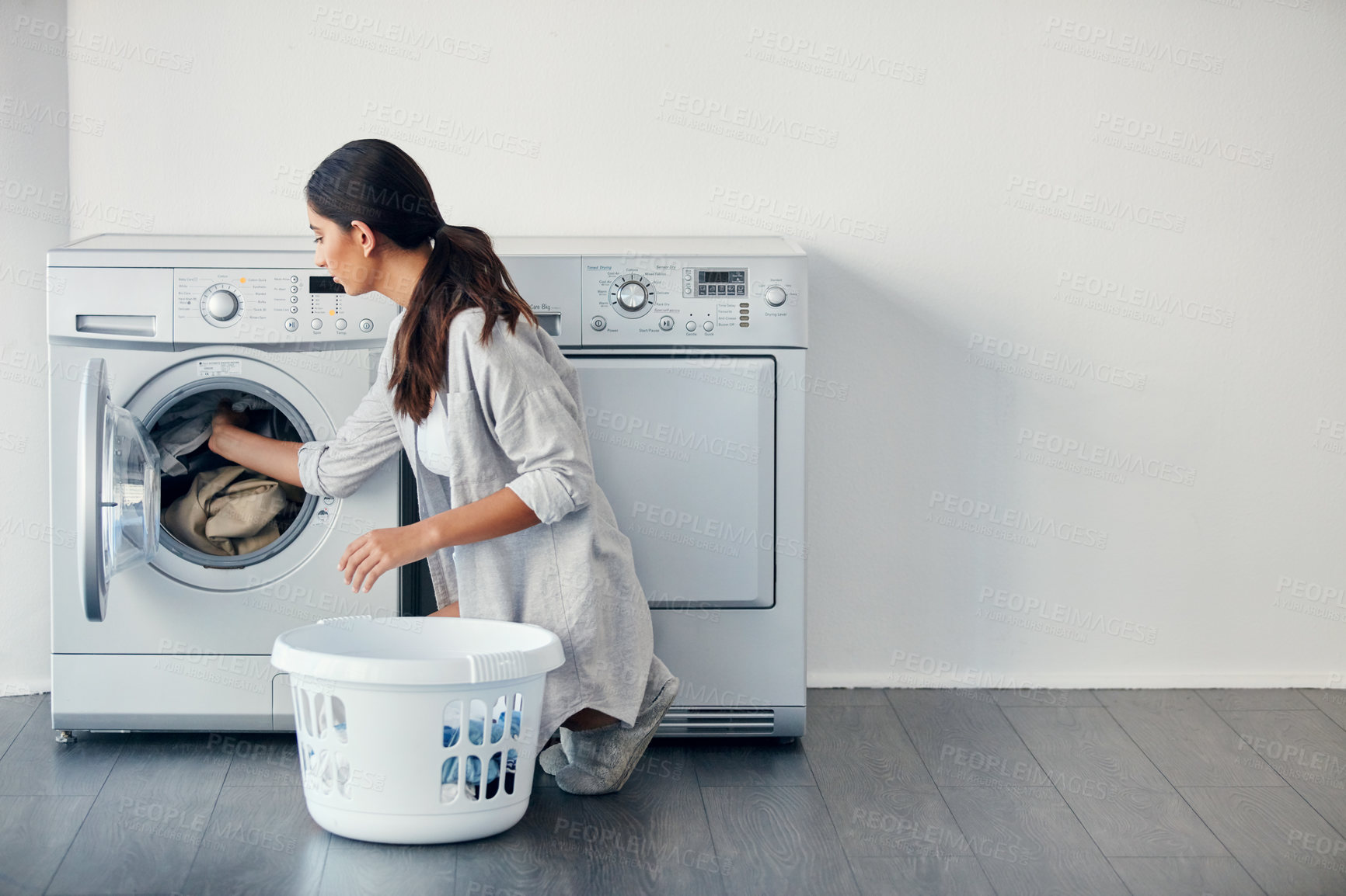 Buy stock photo Shot of a young attractive woman doing her laundry at home