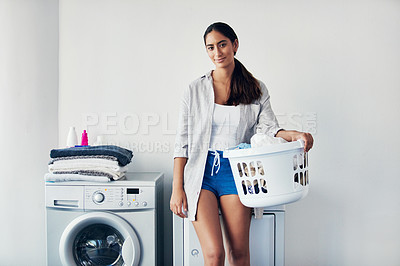 Buy stock photo Shot of a young attractive woman doing her laundry at home