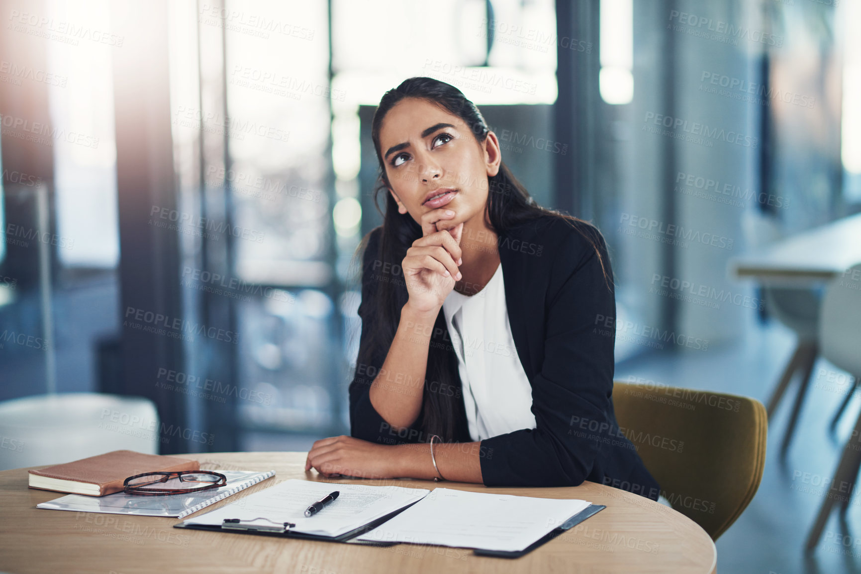 Buy stock photo Shot of a young businesswoman looking thoughtful while working in an office