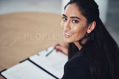 Buy stock photo Portrait of a young businesswoman going through some paperwork in an office